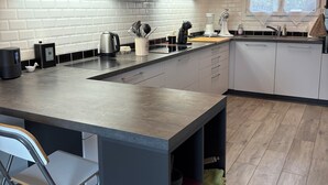 Een moderne keuken met een groot kookeiland, roestvrijstalen apparatuur en een raam met uitzicht op groen.