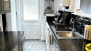 A modern kitchen with a central island, stainless steel appliances, and a large window.