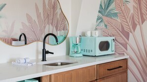 Une salle de bain moderne avec un lavabo, un miroir et une machine à café de couleur turquoise.