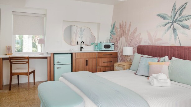 Une chambre à coucher comprenant un lit, un bureau, une chaise, une commode et un four à micro-ondes.