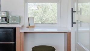 A compact kitchen with a built-in fridge, a coffee maker, and a window with a view of trees.