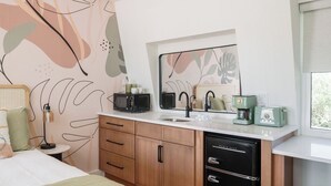 A modern kitchen with a microwave, toaster, and coffee maker on the counter, wooden cabinets, and a sink.