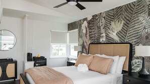 A neatly arranged bedroom with a bed, bedside tables, a ceiling fan, and a window with a view. - The Ocean Queen Studio -5 min walk to beach! (St. Augustine)