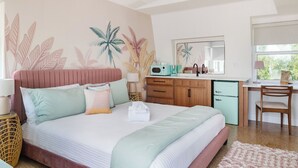 Een slaapkamer met een bed, een bureau, een stoel, een magnetron en een kleine koelkast.