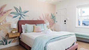 Un dormitorio con cama, mesita de noche, ventana y puerta.
