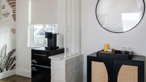 A modern bathroom with a white vanity, a black cabinet with wicker baskets, and a round mirror. - The Vilano Queen Studio - 5 min walk to beach! (St. Augustine)