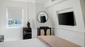 A bedroom with a bed, a dresser, a mirror, a TV, and a window with blinds. - The Vilano Queen Studio - 5 min walk to beach! (St. Augustine)