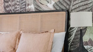 A bed with a woven headboard, a bedside lamp, and a nightstand with drawers. - The Castillo Queen Studio -5 min walk to beach! (St. Augustine)