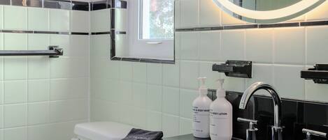 A modern bathroom with a black sink, chrome fixtures, and white tiled walls.