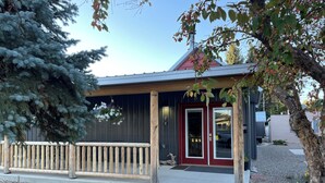 A building with a red door, a wooden porch, and a gravel pathway. - Spacious Convenient Downtown Cody Location (Cody)