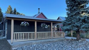 A lodge with a covered porch, a chimney, and a large evergreen tree. - Spacious Convenient Downtown Cody Location (Cody)