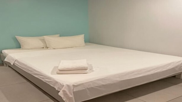 A single bed with white bedding in a room with teal and white walls. - ML Suites Cebu (Cebu City)