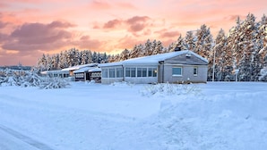 Une rangée de chalets se dressant au milieu d’un paysage enneigé, avec des arbres en arrière-plan.