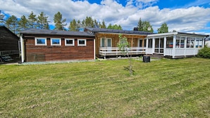 Une cabane en bois avec une véranda et une cour clôturée.