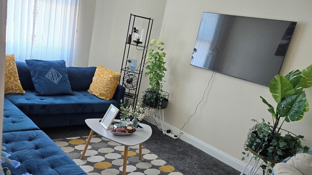 A living room with a blue sofa, a coffee table, and a TV on the wall. - A 2beds luxury stylish apartment in queen street Wolverhampton (Featherstone)