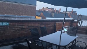 A rooftop patio with a table and chairs, an umbrella, and a sign indicating an exit. - A 2beds luxury stylish apartment in queen street Wolverhampton (Featherstone)