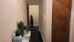 A hallway with a wooden door, a small table with plants, and a decorative wall piece. - A 2beds luxury stylish apartment in queen street Wolverhampton (Featherstone)