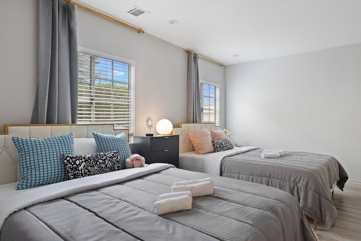 A bedroom with two beds, a nightstand, and a bedside lamp.