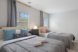 A bedroom with two beds, a nightstand, and a bedside lamp.