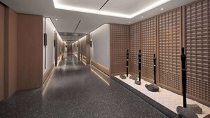 Ein moderner Hotelkorridor mit poliertem Boden, Holzpaneelausstattung und einer Reihe schwarzer Säulen.