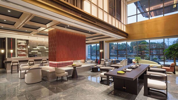 Eine geräumige Lobby mit hoher Decke, modernen Möbeln und großen Fenstern mit Blick ins Freie.
