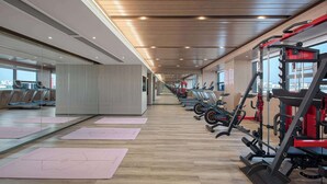 Ein Fitnessstudio mit Trainingsgeräten, Laufbändern und Yogamatten.