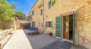 A stone building with a door, a window, and a ping pong table in the courtyard.