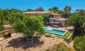 A villa with a swimming pool, outdoor seating, and a stone wall.