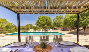 A poolside dining area with a table set for two, overlooking a swimming pool.