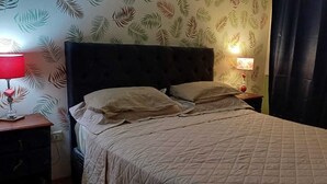 Un lit bien fait, avec une couvre-lit matelassé et deux oreillers, de part et d’autre duquel se trouvent des tables de chevet avec des lampes.