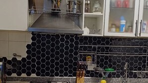 Une cuisine équipée d’une cuisinière à gaz, d’un four et d’un four à micro-ondes. On y trouve des placards avec des portes en verre, un évier et un pare-feu recouvert de carreaux hexagonaux.