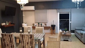 Un salon moderne comprenant une table à manger, des chaises, un canapé, un téléviseur et un balcon.