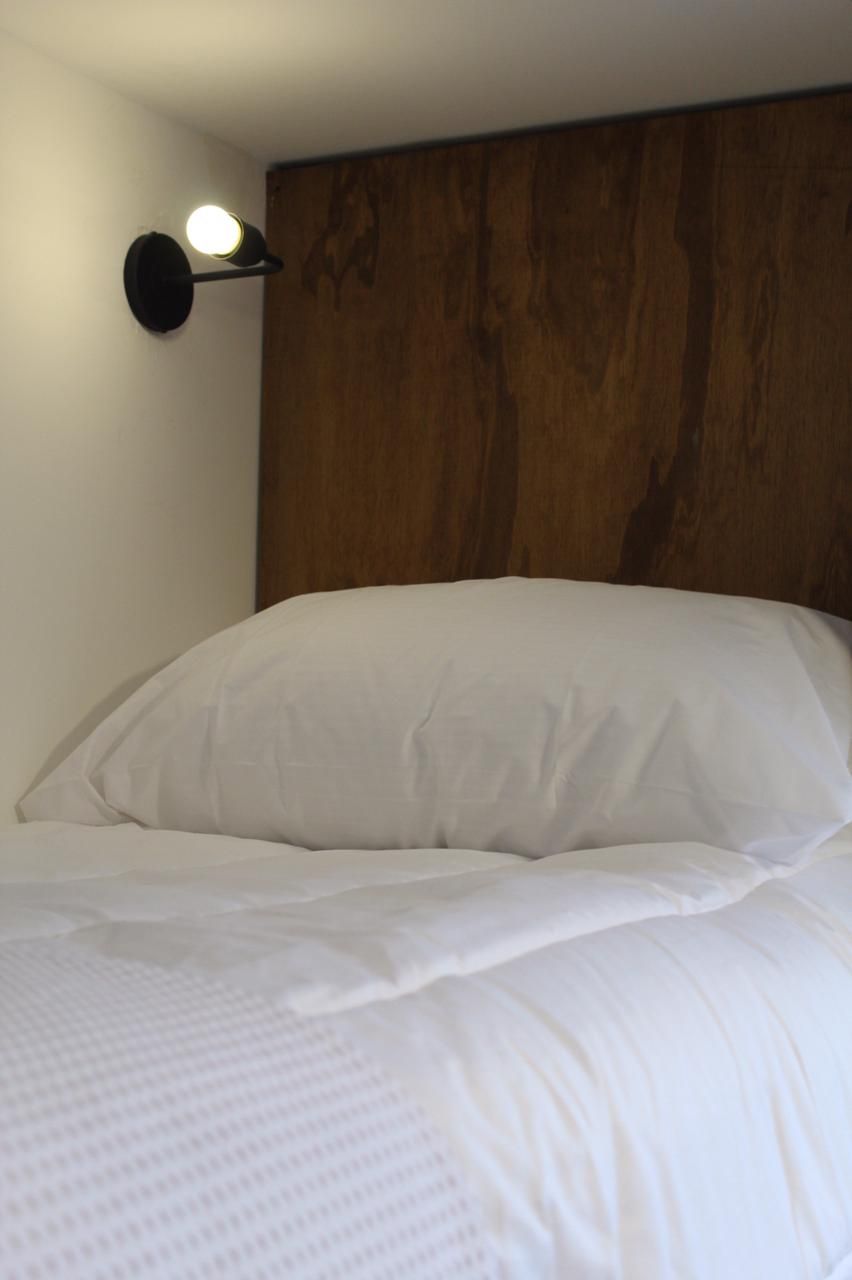 Una cama bien hecha con ropa blanca y cabecero de madera.