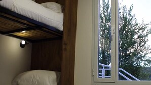 A bunk bed room with a large window, wooden walls, and a light fixture.