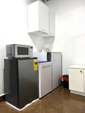 Compact kitchenette with a refrigerator, microwave, sink, and cabinet.