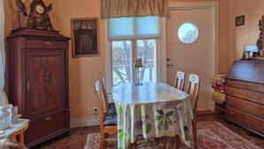 A dining room with a round table, chairs, a wooden cabinet, a clock, and a window with a view of trees. - 2 bedroom gorgeous home in åsensbruk (Åsensbruk)