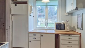 A compact kitchen with a refrigerator, a microwave, a small cabinet with drawers, and a window with a view of the outside. - 2 bedroom gorgeous home in åsensbruk (Åsensbruk)