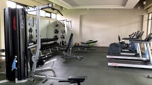 A gym with various exercise equipment including a squat rack, dumbbells, and treadmills.