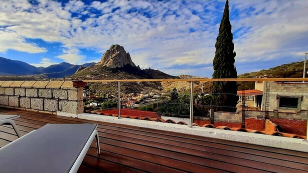 Une terrasse sur le toit offrant une vue sur une montagne, un grand arbre et une ville en contrebas.