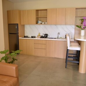 Cocina moderna con armarios de madera, refrigerador de acero inoxidable, salpicadero de mármol y una zona de bar con una silla blanca.