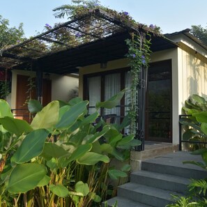 A house with a covered porch, steps leading to the entrance, and lush green plants in the foreground. - Sarga Earthing Resort (Cipanas)
