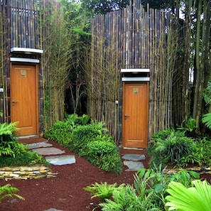 Two wooden doors with a bamboo fence and a stone pathway leading to them. - Sarga Earthing Resort (Cipanas)