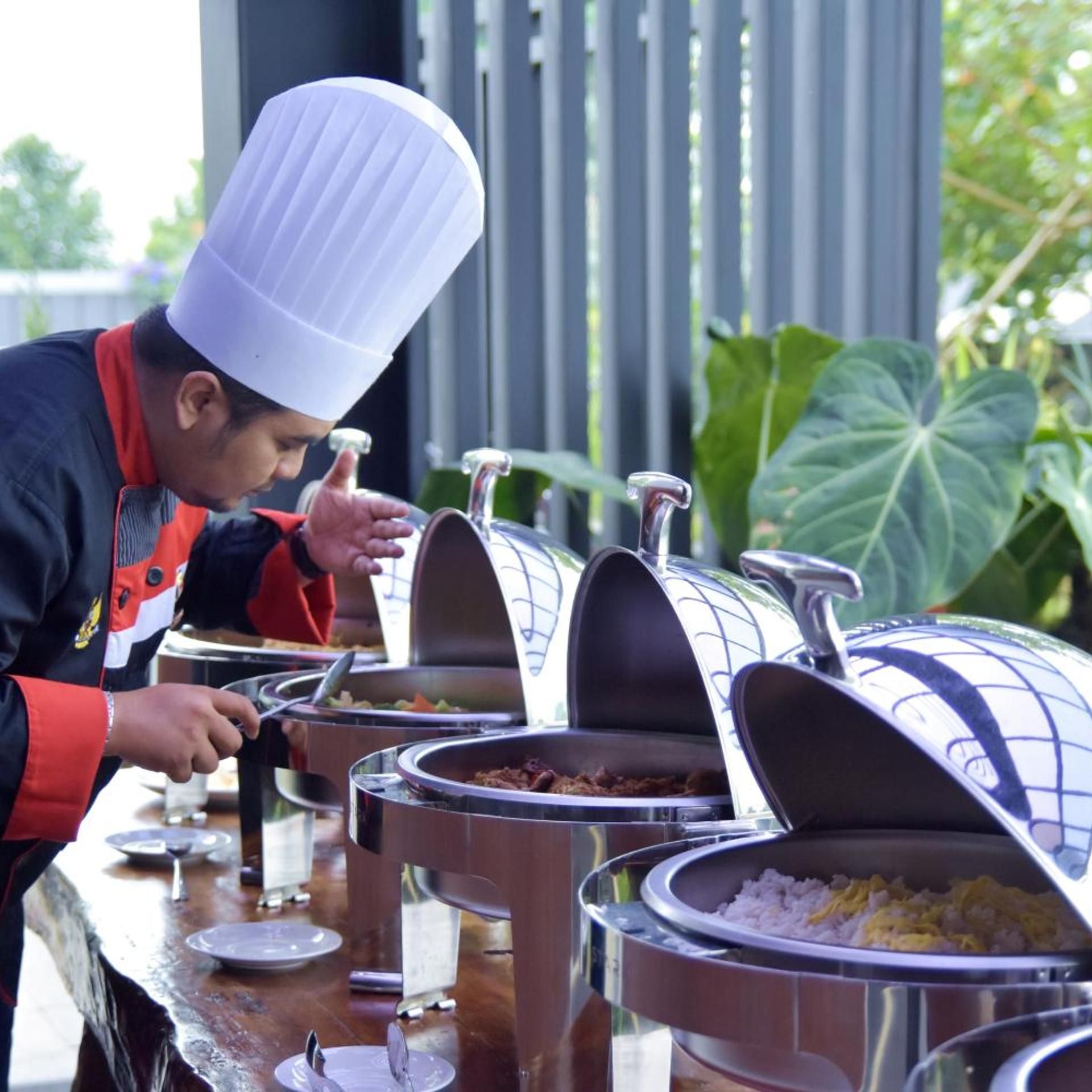A buffet setup with multiple food dispensers and a person serving food.