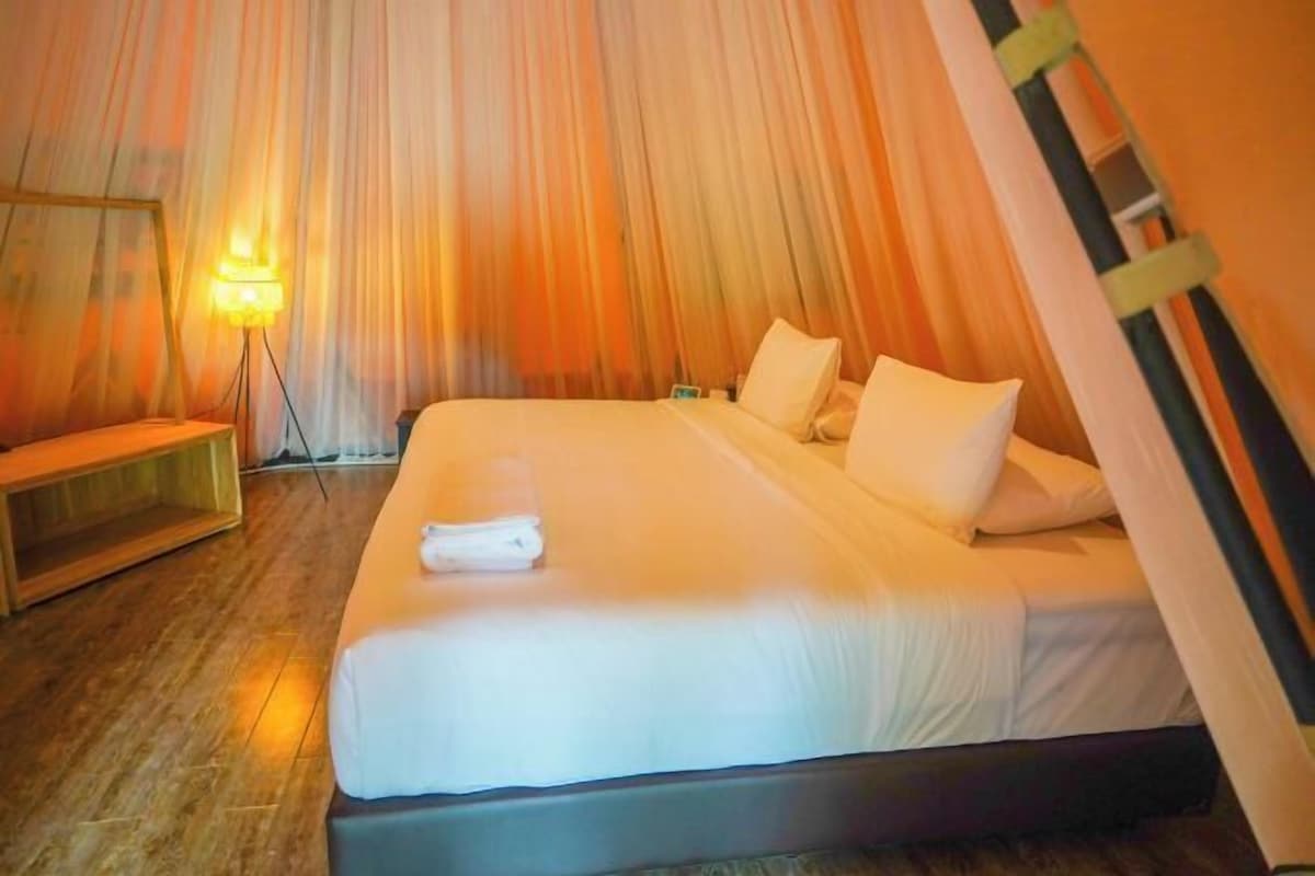 A single bed with white bedding, a bedside lamp, and a wooden bench.