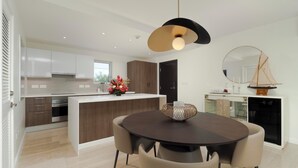 Une cuisine moderne avec des meubles blancs, un îlot central en bois et un coin repas comprenant une table ronde et des chaises.
