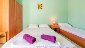 A room with a bed, two pillows, a nightstand with a lamp, a wooden wardrobe, and a framed picture on the wall. - Nice apartment in Povljana with WiFi (Povljana)