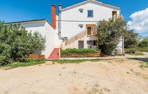 Stunning two-story residence with a charming brick chimney and a wooden staircase leading to a balcony.