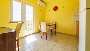 Una habitación luminosa de color amarillo con una mesa de comedor y sillas, una ventana con vistas y un adorno rojo en la pared.