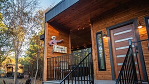 A wooden cabin with a porch, a sign reading "Howdy Y'all", and a staircase leading to the entrance.