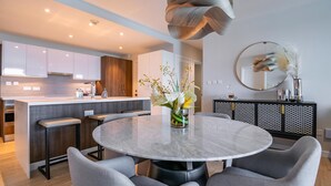 A modern kitchen with a central island, bar stools, and a round dining table with chairs.